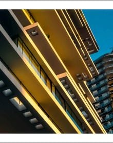 Small child facing sea waves crashing into low wall on pale blue cover, of 'Fadia Ahmad. Beyrouth | Beirut', by Editions Norma.