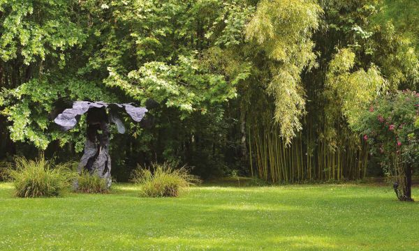 Sculpture of male figure with hand on face, surrounded by green garden foliage, on cover of 'La Petite Escalère, Garden of the Haims', by Editions Norma.
