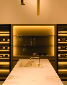 Minimalist interior, marble table, tall wine rack unit, lit fireplace, on cover of 'Bespoke Spaces for Wine', by Beta-Plus.