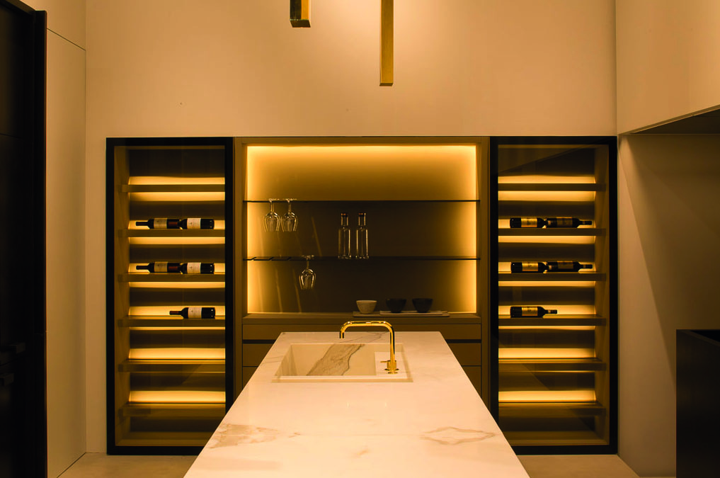 Minimalist interior, marble table, tall wine rack unit, lit fireplace, on cover of 'Bespoke Spaces for Wine', by Beta-Plus.