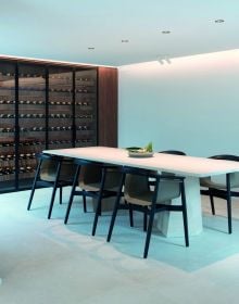 Minimalist interior, marble table, tall wine rack unit, lit fireplace, on cover of 'Bespoke Spaces for Wine', by Beta-Plus.