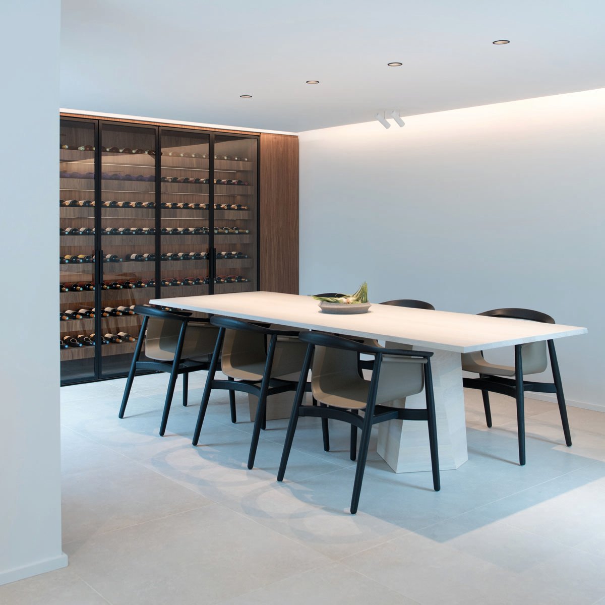 Minimalist interior, marble table, tall wine rack unit, lit fireplace, Bespoke Spaces for Wine in white font to centre right