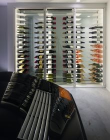 Minimalist interior, marble table, tall wine rack unit, lit fireplace, on cover of 'Bespoke Spaces for Wine', by Beta-Plus.