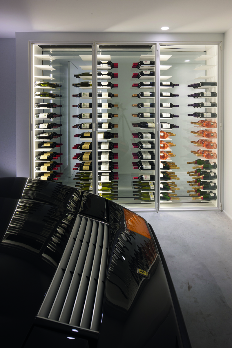 Minimalist interior, marble table, tall wine rack unit, lit fireplace, on cover of 'Bespoke Spaces for Wine', by Beta-Plus.