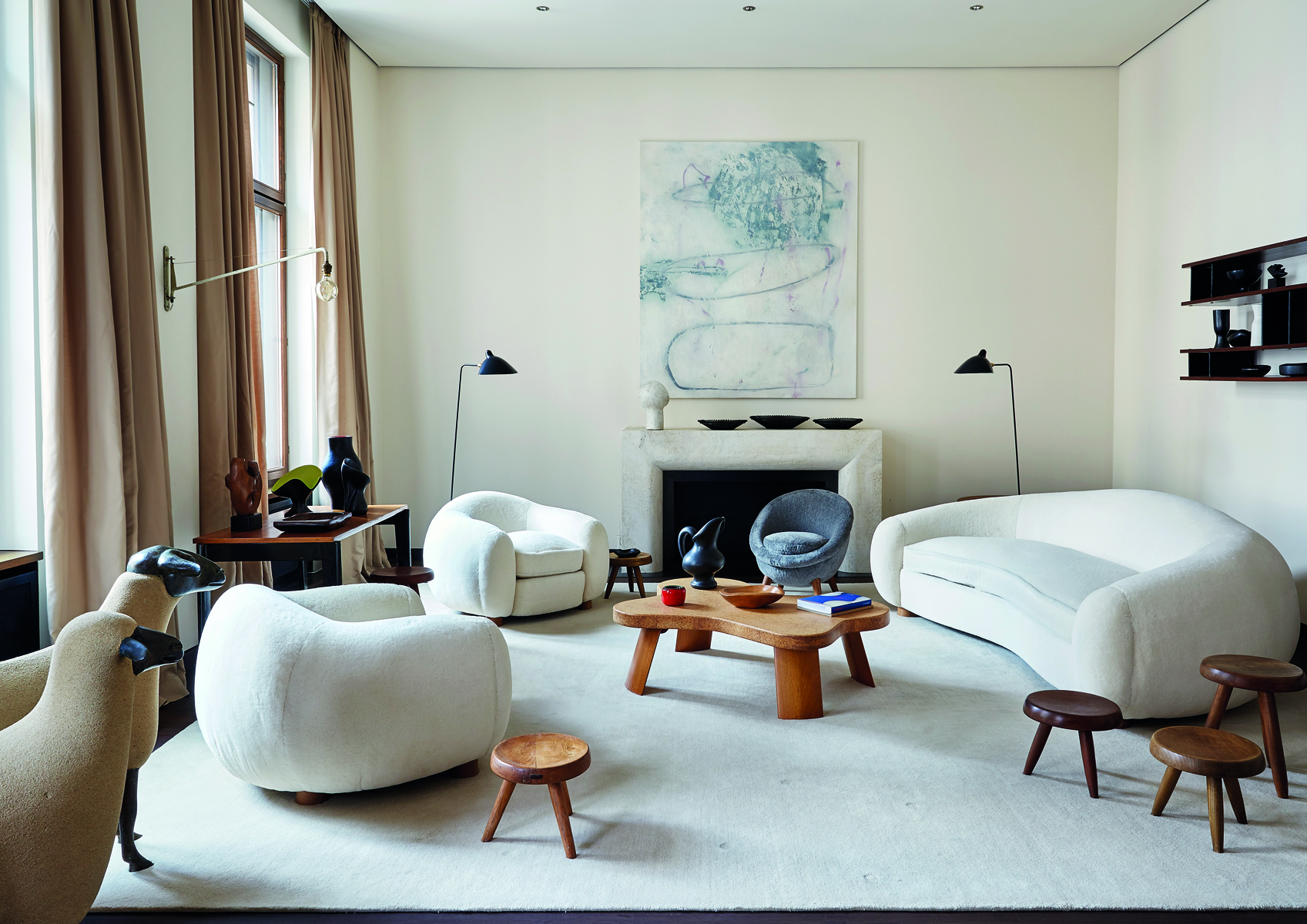 White curved sofa, with three wood stools, cream fire surround, on cover of 'Rendez-Vous Artists & Creatives at Home', by Beta-Plus.