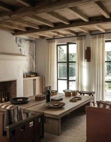 Linen book cover of Les Amandiers Home, Timeless Interiors, with interior living room with tan leather chairs, fireplace, and low wood coffee-table. Published by Beta-Plus.