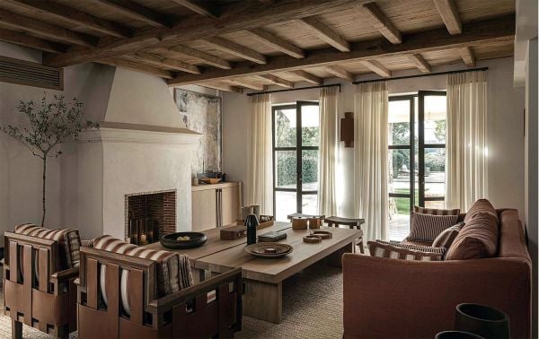 Linen book cover of Les Amandiers Home, Timeless Interiors, with interior living room with tan leather chairs, fireplace, and low wood coffee-table. Published by Beta-Plus.