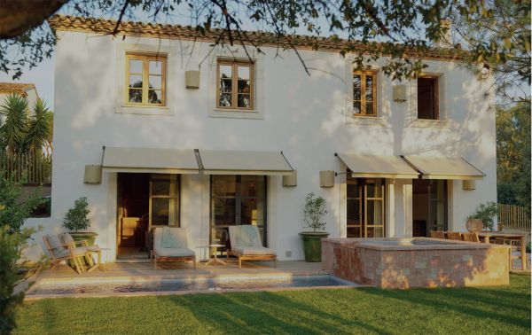 Linen book cover of Les Amandiers Home, Timeless Interiors, with interior living room with tan leather chairs, fireplace, and low wood coffee-table. Published by Beta-Plus.