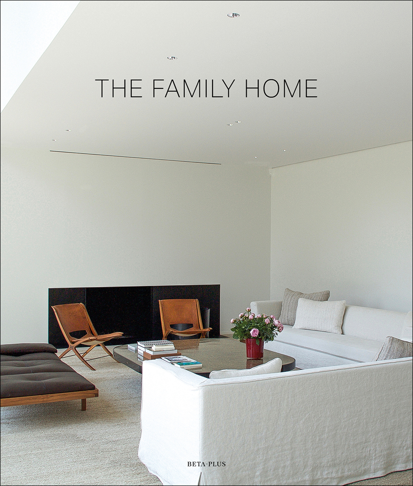 Bright minimalist interior space, white linen covered sofas, brown chairs, THE FAMILY HOME in black font above.