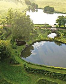 Book cover of Michel Delvosalle Garden & Landscape Architect, with a green landscaped garden with curved waterway. Published by Beta-Plus.