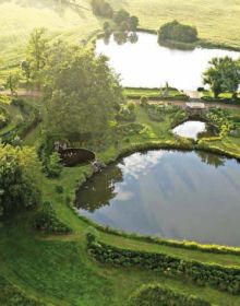 Green landscaped garden with curved waterway, on landscape cover of 'Michel Delvosalle Garden & Landscape Architect', by Beta-Plus.