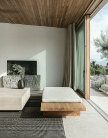 Chair and barrel table with drink on top, swimming pool, sea view behind, tall trees either side, on cover of 'Living by the Sea', by Beta-Plus.