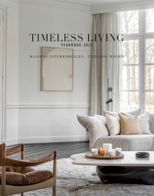White and cream interior living room with low coffee table, 'TIMELESS LIVING YEARBOOK 2023', in black font above.