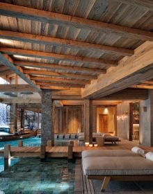 Book cover of Exclusive Living in the Mountains, with interior of wood chalet with cream sofa, and view over mountains. Published by Beta-Plus.