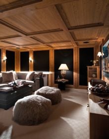 Modern interior of wood chalet with cream sofa chairs, view over mountains, on cover of 'Exclusive Living in the Mountains', by Beta-Plus.