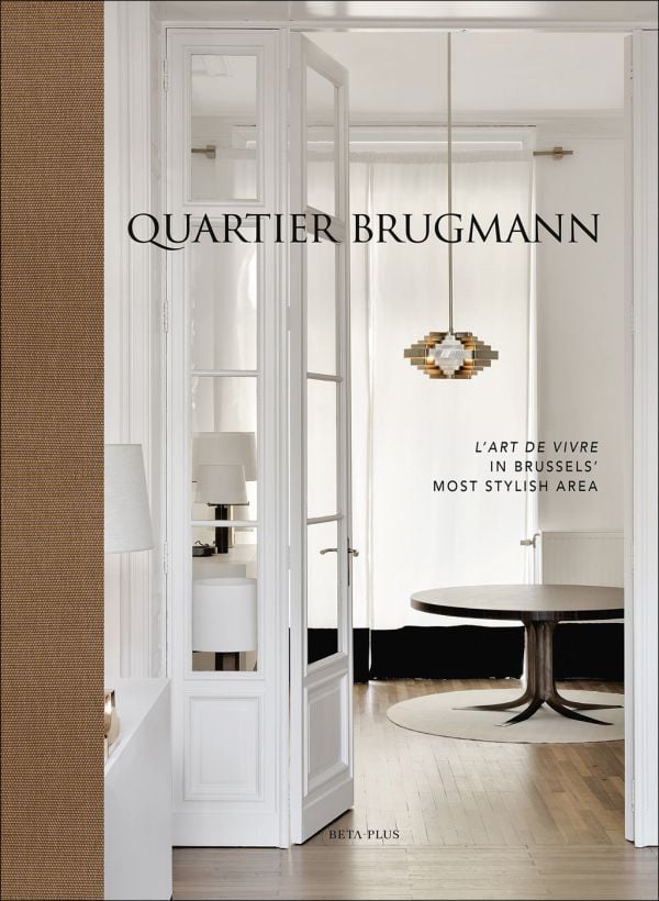 Book cover of Quartier Brugmann, L'Art de Vivre in Brussels' Most Stylish Area, with a white interior living room with wood floor, coffee-table, and low hanging light. Published by Beta-Plus.