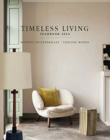Fluffy cream covered chair with yellow cushion, floor lamp, on cover of 'Timeless Living Yearbook 2024', by Beta-Plus.