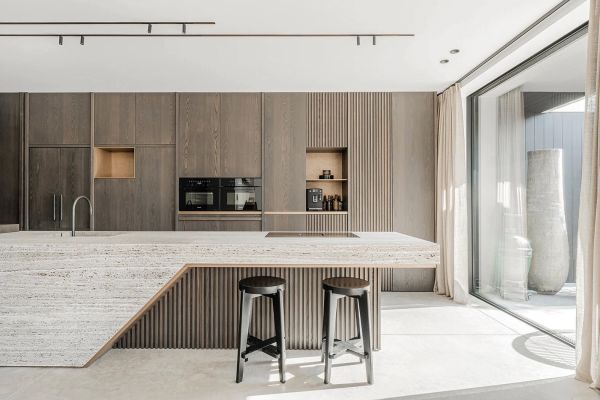 Interior with cream textured walls, with arched double doors, wooden chair and table, on cover of 'Contemporary Living Yearbook 2024', by Beta-Plus.