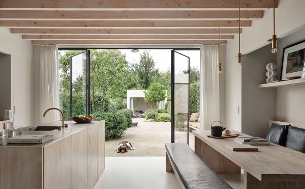 Book cover of am designs; featuring an interior living room with wood ceiling beams above a long table with chairs. Published by Beta-Plus.