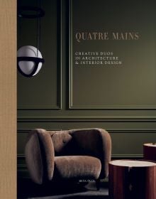 Book cover of Quatre Mains: Creative Duos In Architecture & Interior Design; featuring an interior room with dark green panelled walls and a large brown armchair. Published by Beta-Plus.
