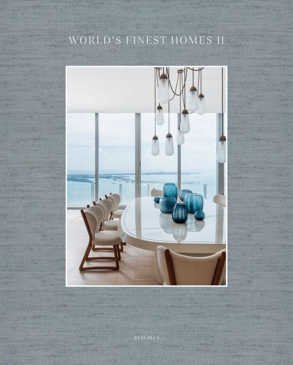 Book cover of World's Finest Homes II; featuring a modern interior living space with large dining table, and views out to a river. Published by Beta-Plus.
