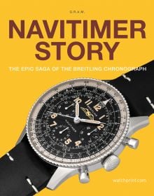 Black and silver Navitimer watch, on yellow cover, NAVITIMER STORY in brown font above