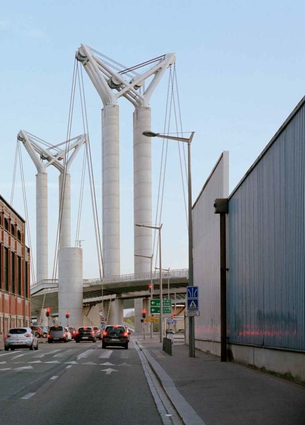 Man on white plinth taking photo of landscape, on white cover, Creatures of the City in black font above