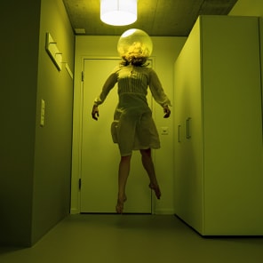 Book cover of Promenades: Photography and Architecture; featuring a woman in sparkly red dress peering through taupe drapes. Published by Park Books.