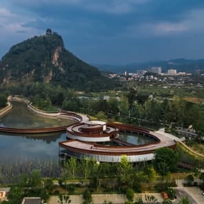 Row of wood buildings, steps leading up towards hilly landscape, The Songyang Story in black font above.