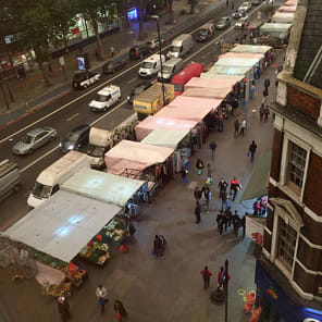High perspective street view in London with traffic on road and Daniela Keiser London – Being in the Library in white font with text to right in white
