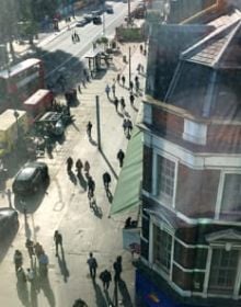 High perspective street view in London with traffic on road and Daniela Keiser London – Being in the Library in white font with text to right in white