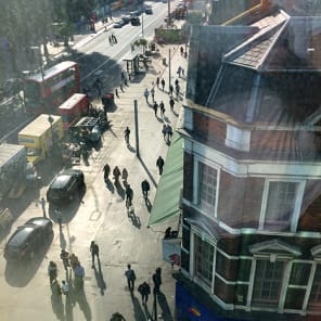 High perspective street view in London with traffic on road and Daniela Keiser London – Being in the Library in white font with text to right in white