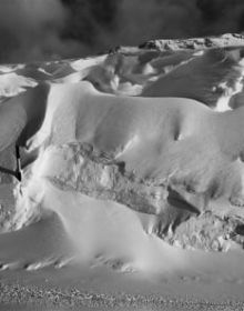 Black and white atmospheric photo of mountainous landscape with white mist and Bernina transversal in white font in cross shape
