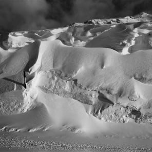 Black and white atmospheric photo of mountainous landscape with white mist and Bernina transversal in white font in cross shape
