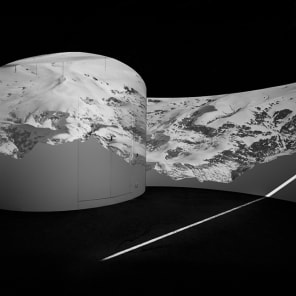 Black and white atmospheric photo of mountainous landscape with white mist and Bernina transversal in white font in cross shape