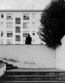 Black and white image of white high rise building complex surrounded by large trees with Hidden in Plain Sight in light orange font