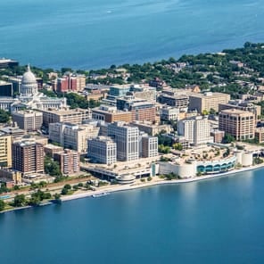 Book cover of Living Cities: Three Centuries of Park Systems, with an aerial view of brown fields, green space, and rivers. Published by Park Books.
