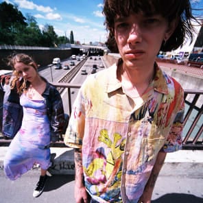 Head and shoulder green filtered shot of model, closed eyes in dress and long earrings, Wild Thing in white font below.