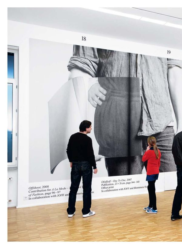 Black and white image of folded envelope booklet with legs in stripy tights to left and obscured capital A with speech marks