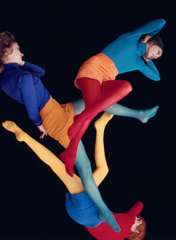 Black and white image of folded envelope booklet with legs in stripy tights to left and obscured capital A with speech marks