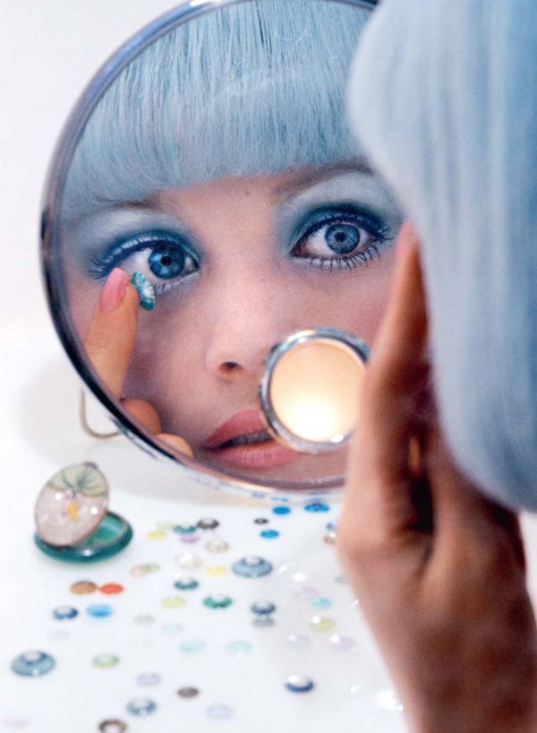 Black and white image of folded envelope booklet with legs in stripy tights to left and obscured capital A with speech marks