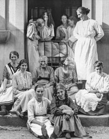 Book cover of Behind Walls: Photography in Psychiatric Institutions from 1880 to 1935, with a man in long white smock with waistcoat, and man in tribal dress, standing in doorway. Published by Scheidegger & Spiess.