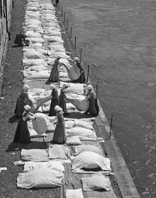 Book cover of Behind Walls: Photography in Psychiatric Institutions from 1880 to 1935, with a man in long white smock with waistcoat, and man in tribal dress, standing in doorway. Published by Scheidegger & Spiess.