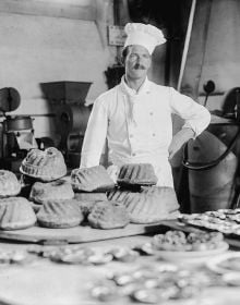 Book cover of Behind Walls: Photography in Psychiatric Institutions from 1880 to 1935, with a man in long white smock with waistcoat, and man in tribal dress, standing in doorway. Published by Scheidegger & Spiess.