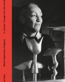 Book cover of Simon Baur Meret Oppenheim Enigmas A Journey Through Life and Work, with the artist and photographer smiling, in front of sculpture. Published Scheidegger & Spiess.