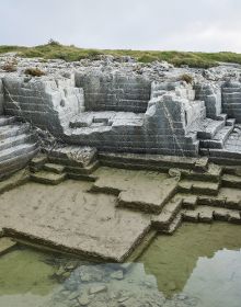 Wall of stone blocks, brick pile below, on white cover, Georg Aerni Silent Transition in beige font below