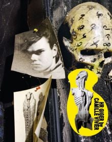 Photograph of H.R Giger pinned to wall, skull with black symbols, HR GIGER BY CAMILLE VIVIER, in black font on yellow banner to bottom right.