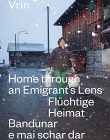 Book cover of Vrin: Home Through An Emigrant's Lens, with a person carrying two containers in snowy weather. Published by Scheidegger & Spiess.