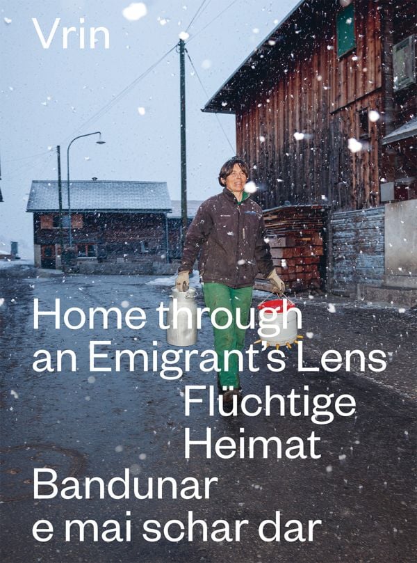 Book cover of Vrin: Home Through An Emigrant's Lens, with a person carrying two containers in snowy weather. Published by Scheidegger & Spiess.