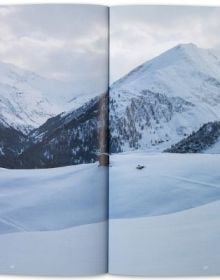 Book cover of Vrin: Home Through An Emigrant's Lens, with a person carrying two containers in snowy weather. Published by Scheidegger & Spiess.